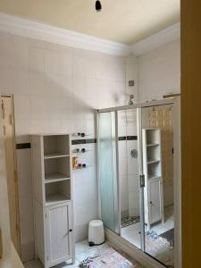 La salle de bains est pourvue d'une douche et d'une porte en verre. dans l'établissement The Manor, à Lomé