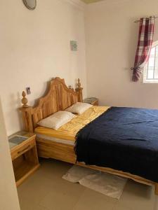 sypialnia z drewnianym łóżkiem i niebieskim kocem w obiekcie The Manor w mieście Lomé