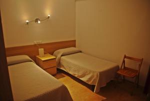 a hospital room with two beds and a chair at Hostal L'Alba in Tossa de Mar