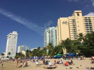 um grupo de pessoas numa praia com edifícios em Tropical Studio at the Beach in Isla Verde em San Juan