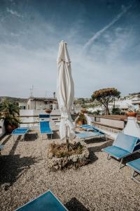 ein weißer Regenschirm und Stühle auf einer Terrasse in der Unterkunft Hotel Casa Giuseppina in Ischia