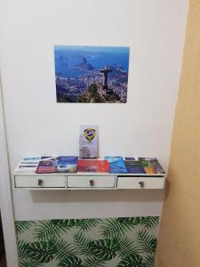 a shelf with books on it with a picture on the wall at Botafogo Guesthouse in Rio de Janeiro