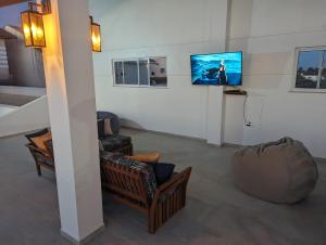 een woonkamer met stoelen en een tv aan de muur bij Pousada Diane in Trairi