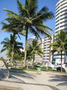 um parque com palmeiras e um banco e edifícios em Vip Residencial - Praia Grande na Praia Grande