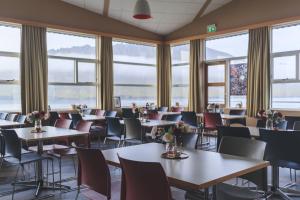 a dining room with tables and chairs and windows at The Cliff Hotel in Neskaupstaður