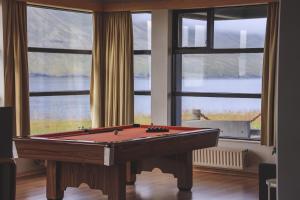 a pool table in a room with windows at The Cliff Hotel in Neskaupsta&eth;ur