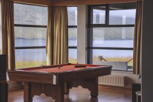 a pool table in a room with windows at The Cliff Hotel in Neskaupstaður