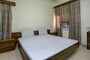 Schlafzimmer mit einem Bett mit weißer Bettwäsche und Vorhängen in der Unterkunft OYO Hotel Friday's in Bathinda