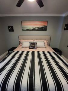 ein Bett mit einer schwarz-weißen gestreiften Bettdecke in der Unterkunft Blue Shark *H12* @ River Oaks Modern 1BR King Apartment in Houston