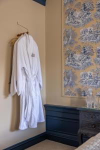 a white robe hanging on a wall next to a bed at Eleven Stafford Street Townhouse in Edinburgh