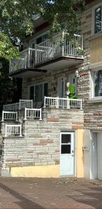 a brick house with a balcony and a white door at Cozy Spacious Work Friendly Lotus with Garden View High speed free Wi Fi and Parking Adjacent to Downtown Montreal in Montreal