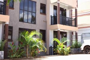 a building with palm trees in front of it at Orchid Suites, Kira in Bulindo