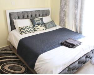 SIMBA'S NOOK - A modern Budget Studio Apartment in Syokimau, Nairobi with Fast WiFi & Netflix - Near the JKIA Airport, SGR Station & Gateway Mall في Syokimau: غرفة نوم بها سرير كبير مع وسائد