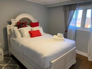 a bedroom with a white bed with red pillows at SUMPTUOUS HOUSE IN BEAUTIFUL NEIGHBORHOOD in Brampton