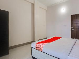 a white room with a bed with a red blanket at OYO Flagship Radhe Radhe Hotels in Kānpur