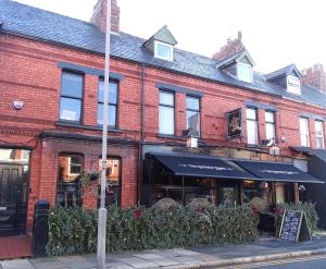 a red brick building with a restaurant on a street at Modern & Stylish Home at the corner of famous Penny Lane in Liverpool in Liverpool