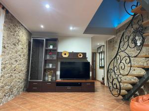 a living room with a television and a stone wall at Casa Costeira in Redondela