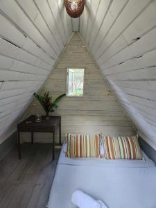 Łóżko w białym pokoju na poddaszu z oknem w obiekcie Recanto do Pontal Camping w mieście Angra dos Reis