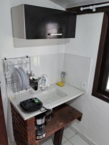 a white sink in a kitchen with a microwave at Chalé do riacho 2 in Penedo