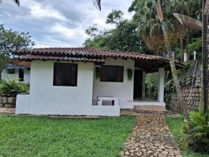 une petite maison blanche avec une cour verdoyante dans l'établissement Chalé do riacho 2, à Penedo