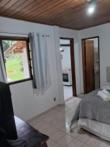 Schlafzimmer mit einem Bett, einem Fenster und einem TV in der Unterkunft Chalé do riacho 2 in Penedo