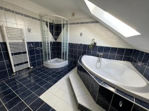 a blue tiled bathroom with a tub and a shower at Dům Julie in Tachov