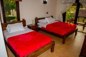 Villas Panaca Portal 1 في كويمبايا: غرفة نوم بسريرين مع شراشف حمراء