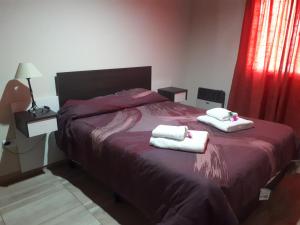 1 dormitorio con 1 cama con toallas en Departamentos San Benito en Malargüe
