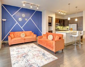 a living room with two orange couches and a kitchen at The Tangerine Dream in Houston