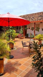 a patio with a table and a red umbrella at La Casona Espacio Bonito in Zapatoca