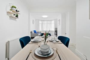 Dunstable 3 bedroom house with Free Parking في دانستابل: غرفة طعام مع طاولة خشبية مع كراسي زرقاء