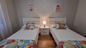 2 Einzelbetten in einem Zimmer mit einer Lampe in der Unterkunft Soleado piso 4 habit a pie de playa Sanxenxo in Sanxenxo