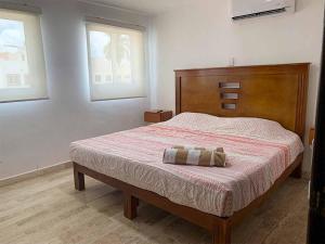 a bedroom with a bed with a wooden headboard and two windows at Casa en Quintas del Mar con acceso a la playa in Mazatlán