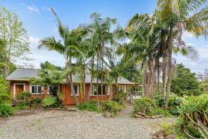 a house with palm trees in front of it at Stillhaven - Kerikeri Riverside Retreat in Kerikeri