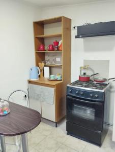 a kitchen with a black stove and a table at Apartamento cerca del Humedal Tres Puentes in Punta Arenas