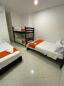 a bedroom with two beds and a chair in it at HOTEL LIGHT PLAZA in Aguachica