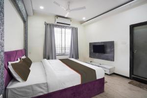 ein Schlafzimmer mit einem großen Bett und einem TV in der Unterkunft Hotel City Pride in Raipur