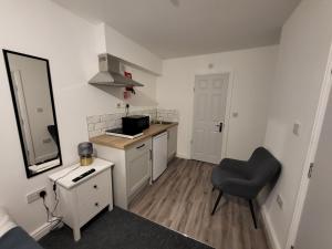una pequeña cocina blanca con silla y espejo en Stay Sleep Rest - Tring Vale en Nottingham