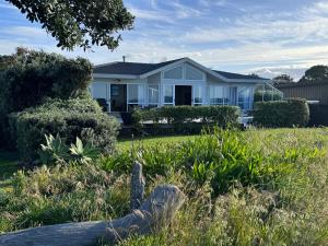 een huis met een tuin ervoor bij Matarangi Beachfront - Matarangi Holiday Home in Matarangi
