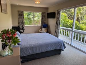 een slaapkamer met een bed en een groot raam bij Matarangi Beachfront - Matarangi Holiday Home in Matarangi