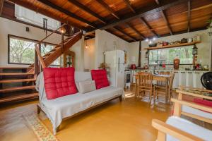 a living room with a white couch with red pillows at Chalé Verde Prána in Brumadinho