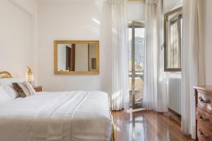 ein weißes Schlafzimmer mit einem Bett und einem Spiegel in der Unterkunft Casa Patrizia Como Lake View - by Relais Di Giada in Como