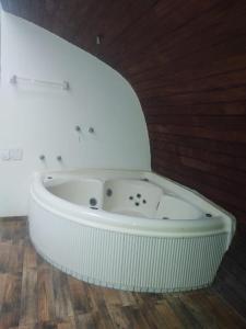 eine weiße Badewanne in einem Zimmer mit Holzboden in der Unterkunft Pousada Vale Encantado Macaé in Macaé