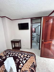 - une chambre avec un lit et une télévision à écran plat dans l'établissement Nuevo Horizonte, à Pasto