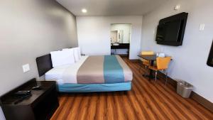 Habitación de hotel con cama, escritorio y TV. en Motel 6-Webster, TX - Houston - Nasa Lake, en Webster
