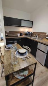 uma cozinha com uma mesa com pratos e copos em Tout confort. Appartement 2 pers. centre-ville em Le Creusot
