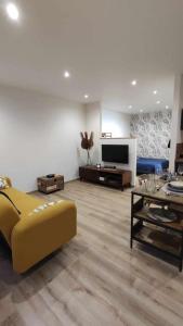 uma sala de estar com um sofá amarelo e uma mesa em Tout confort. Appartement 2 pers. centre-ville em Le Creusot
