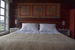 a bedroom with a large bed with two pillows at Estación Hostel in Castro