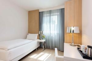ein Hotelzimmer mit einem Bett und einem Fenster in der Unterkunft NH Ludwigsburg in Ludwigsburg