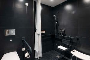 a black bathroom with a toilet and a shower at NH Ludwigsburg in Ludwigsburg
